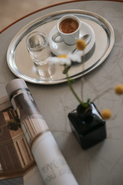 Espresso und Wasserglas auf silbernem Tablett mit Margerite