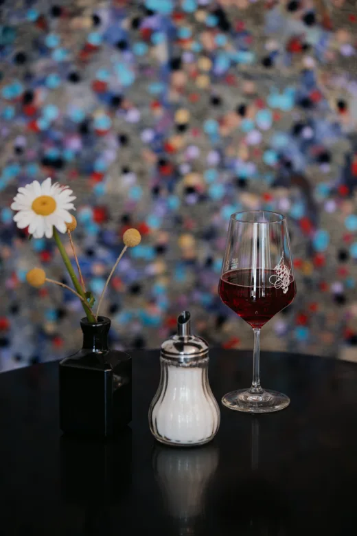 Ein Glas Rotwein vor der bunten Kunstwand im Café Lex