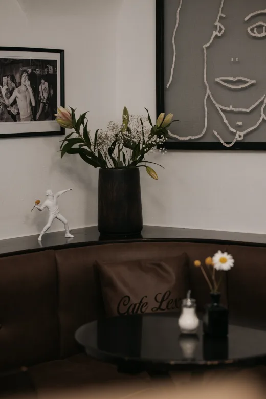 Gemütliche Polsterecke mit Lilien in dunkler Vase und Kunst an der Wand